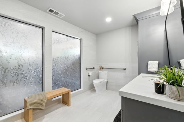 Accessible bathroom in Fresno with frosted floral windows, bench, and modern gray vanity
