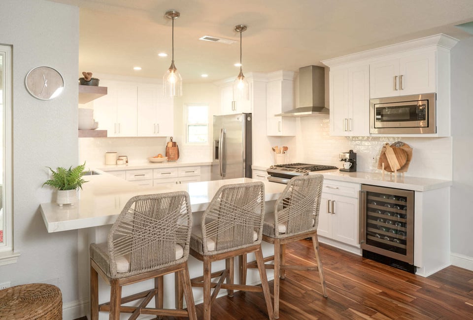 Modern Fresno, CA kitchen featuring a large white island, pendant lighting, stainless appliances, and wine fridge