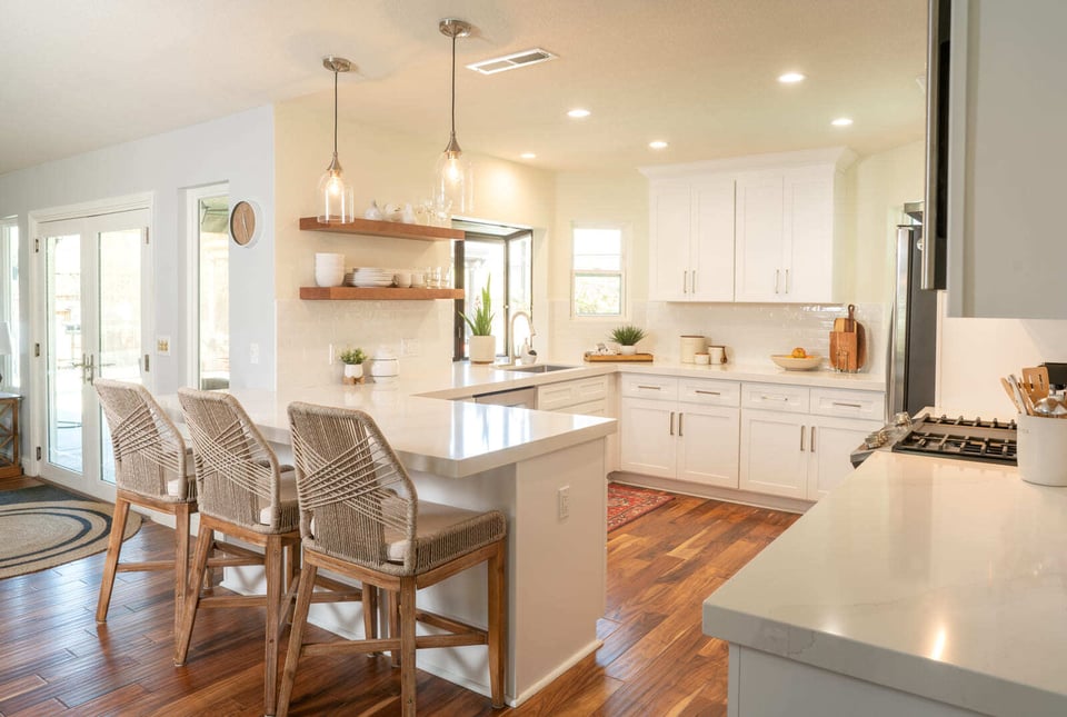 Open-concept Fresno, CA kitchen with white cabinetry, wood floors, island seating, and floating shelves