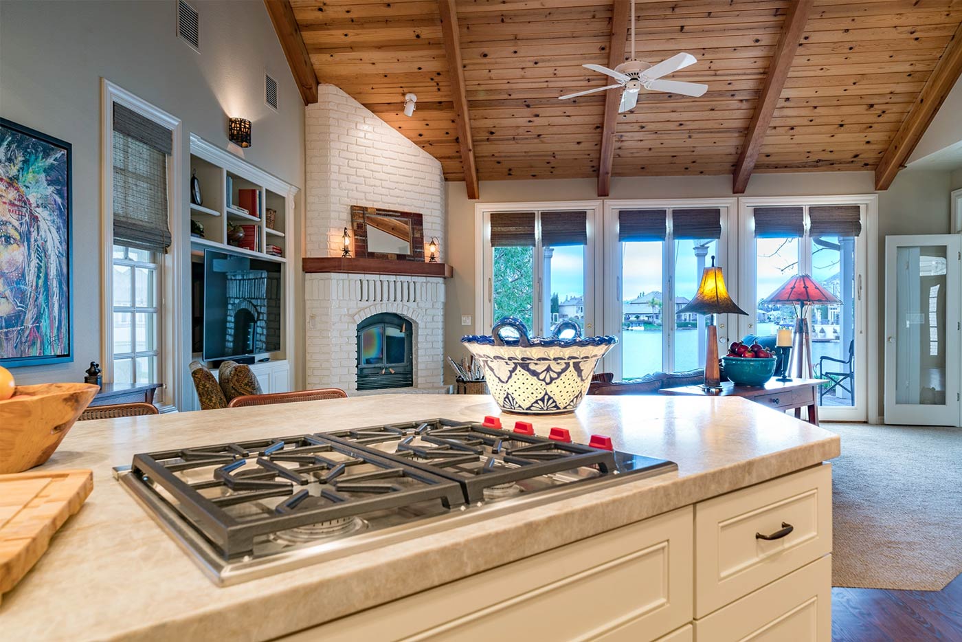 Kitchen with vaulted wood ceiling and lake view in Fresno featuring a cozy fireplace and bright natural lighting