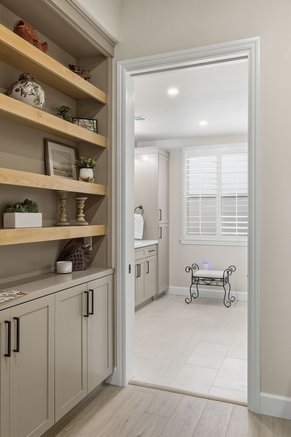 Hallway view of built-in shelves leading into a bright bathroom with neutral finishes in Fresno Hallway view of built-in shelves leading into a bright bathroom with neutral finishes in Fresno