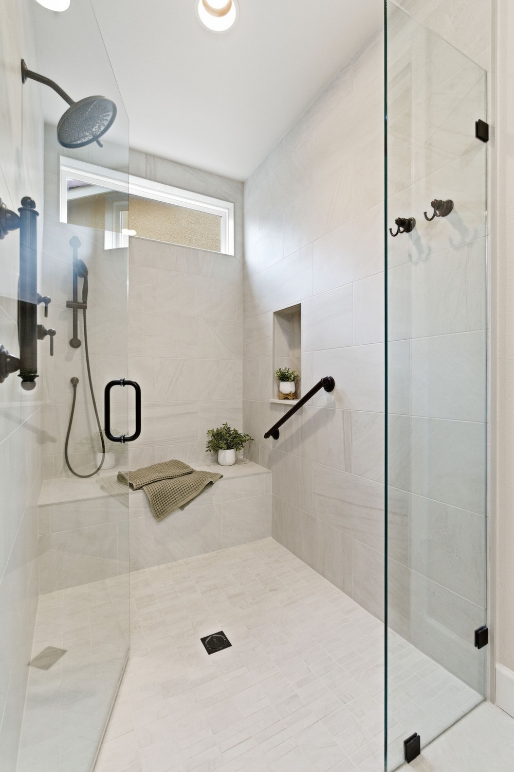 Large tiled walk-in shower with bench, glass enclosure, and black hardware, located in Fresno Large tiled walk-in shower with bench, glass enclosure, and black hardware, located in Fresno
