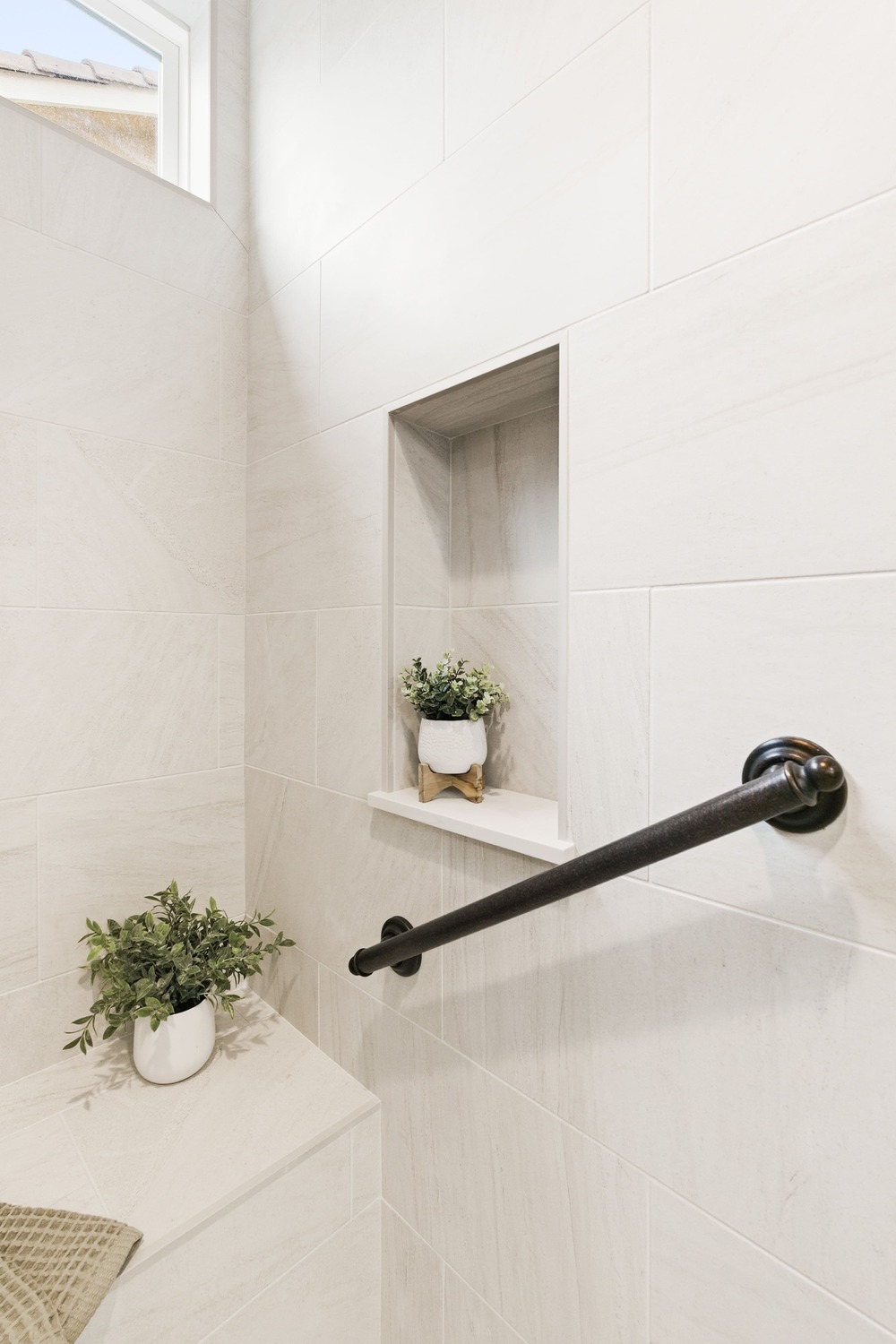 Shower detail showing built-in niche and black grab bar against light tile, located in Fresno CA Shower detail showing built-in niche and black grab bar against light tile, located in Fresno CA