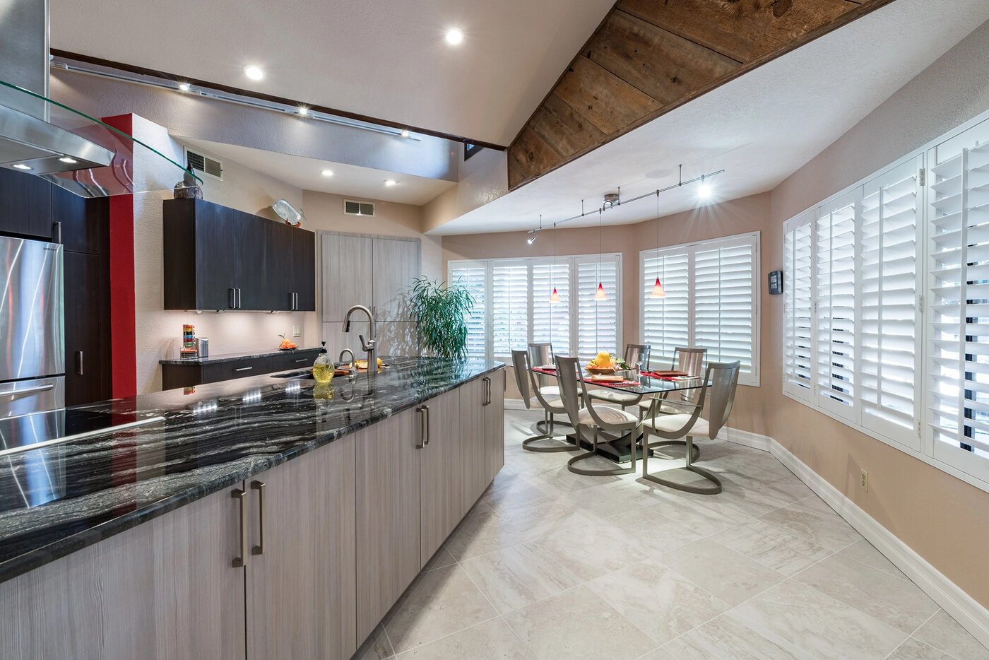 Modern kitchen and dining area in the Fresno area with sleek cabinetry, marble-look flooring, and bold pendant lighting