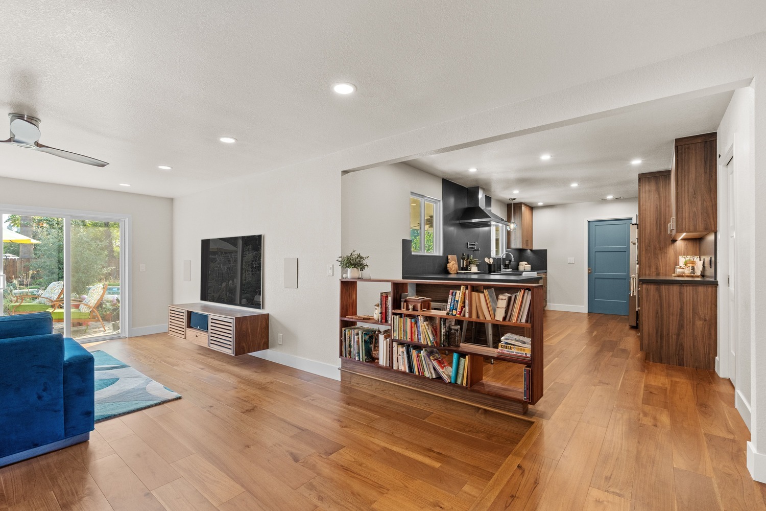 Fresno living room and kitchen with wood floors, blue sectional, and built-in bookshelves