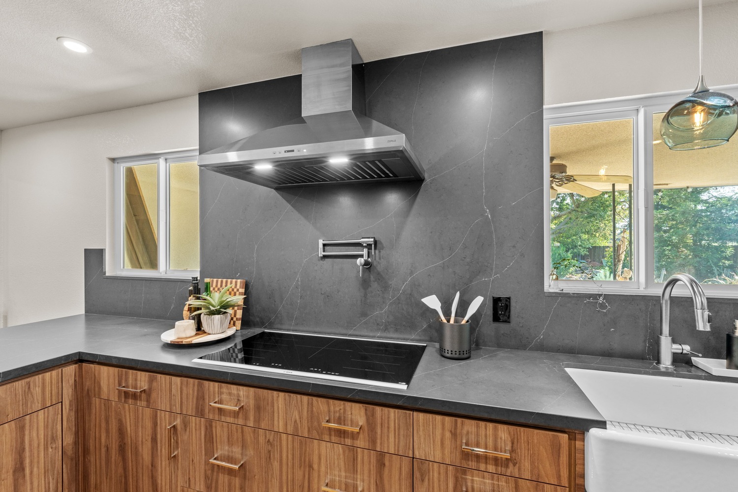 Modern Fresno kitchen featuring dark stone backsplash, induction cooktop, and stainless hood