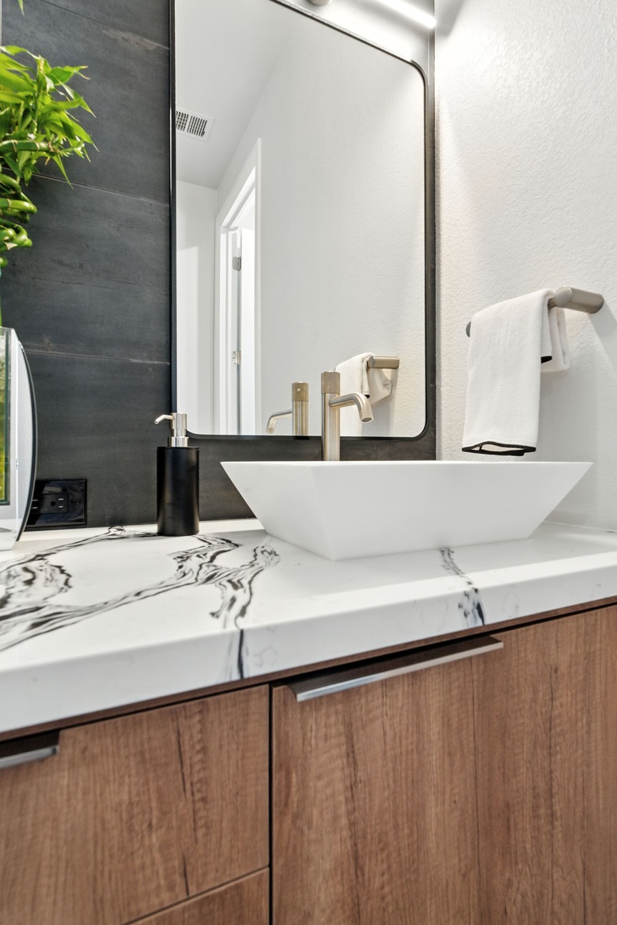 Fresno bathroom with vessel sink, marble pattern countertop, and tall dark tile accent wall