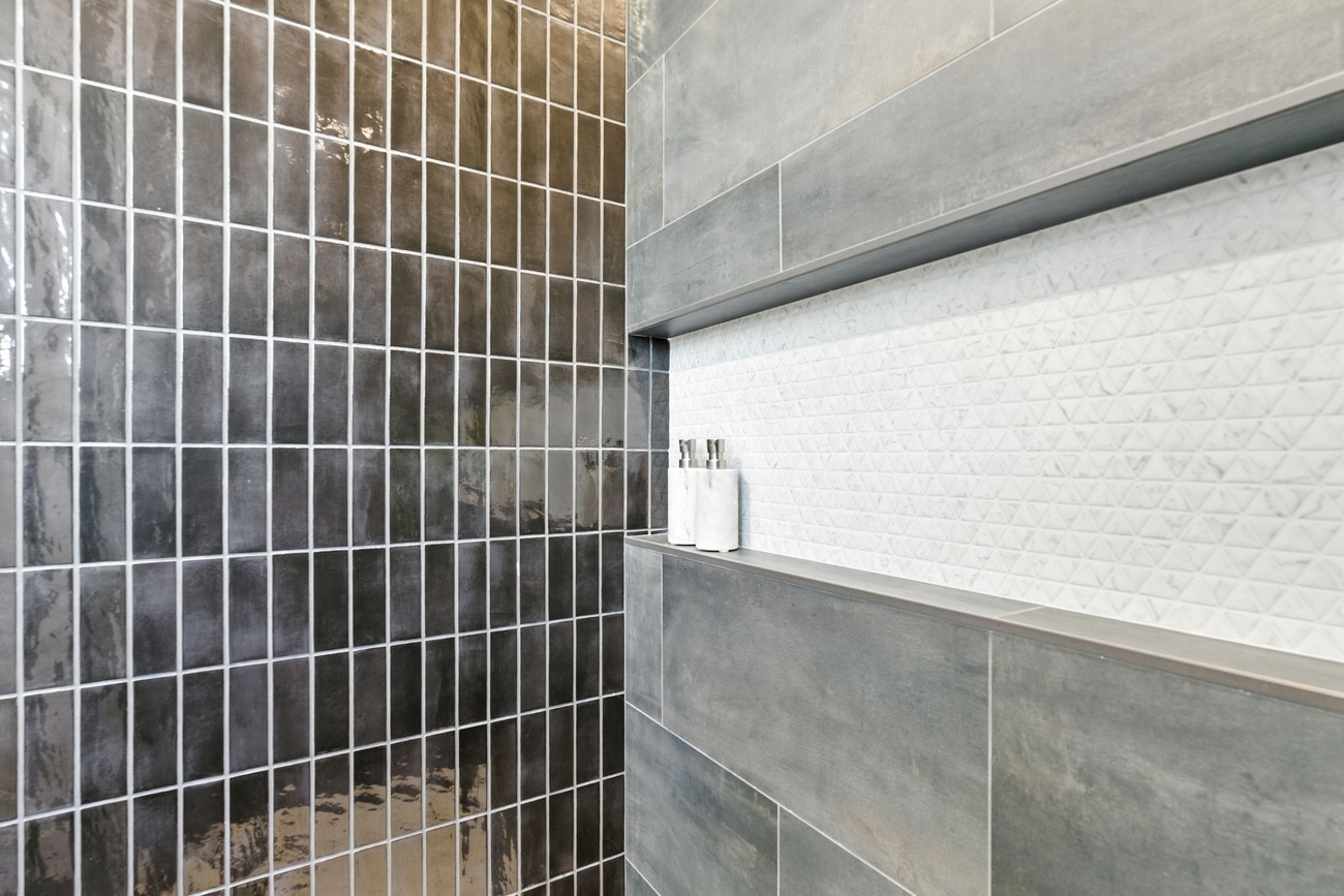 Fresno shower corner with glossy dark tile wall and white textured niche holding dispensers