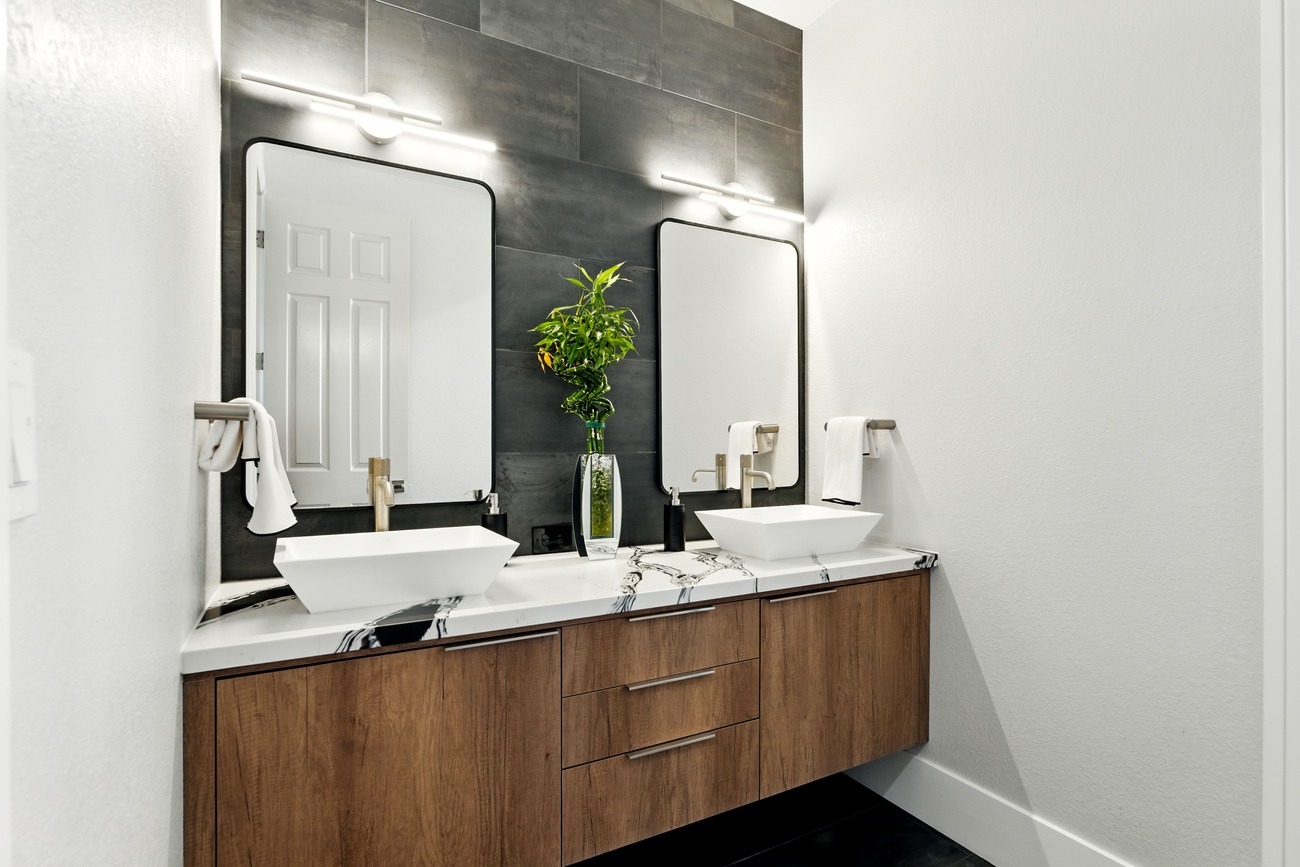Modern Fresno double vanity with vessel sinks, marble style counters, and black tile wall