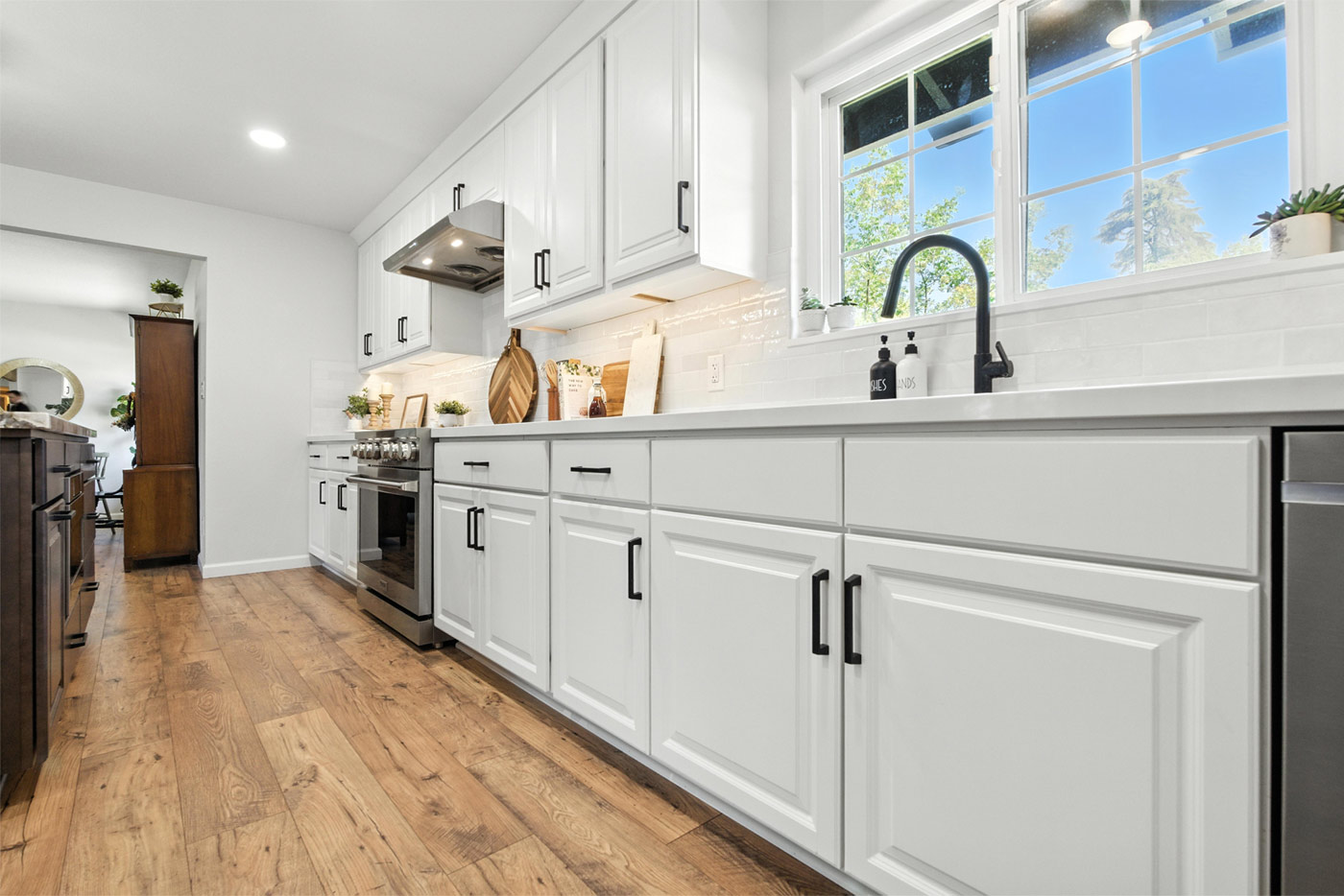 Bright kitchen with white cabinets, wood floors, and black fixtures in a home in Clovis, CA Bright kitchen with white cabinets, wood floors, and black fixtures in a home in Clovis, CA