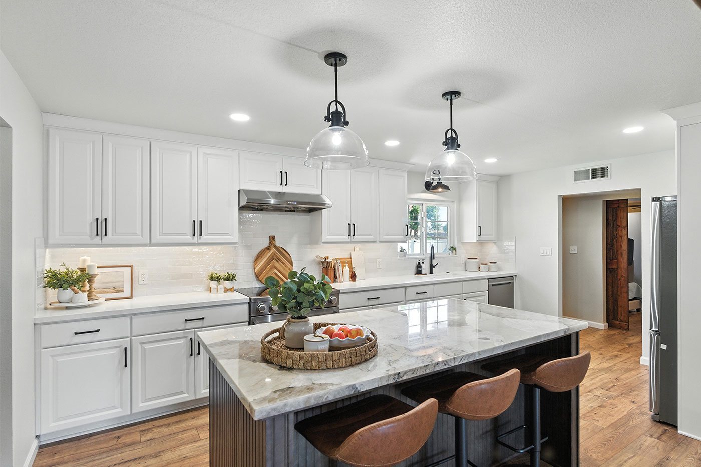 Modern kitchen with large island, pendant lights, and white cabinetry in Clovis, CA Modern kitchen with large island, pendant lights, and white cabinetry in Clovis, CA