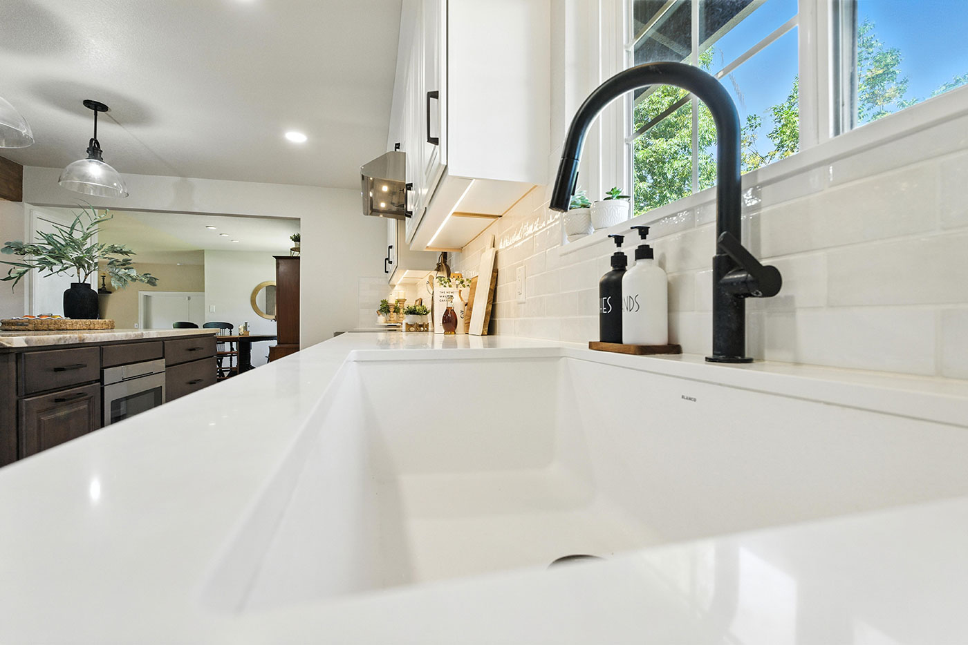 Sleek Clovis, CA kitchen by Imagine Remodeling featuring a farmhouse sink and black faucet under a bright window Sleek Clovis, CA kitchen by Imagine Remodeling featuring a farmhouse sink and black faucet under a bright window
